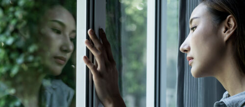 Depressed woman's reflection in window