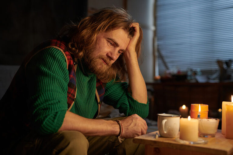 Depressed man contemplating by candles